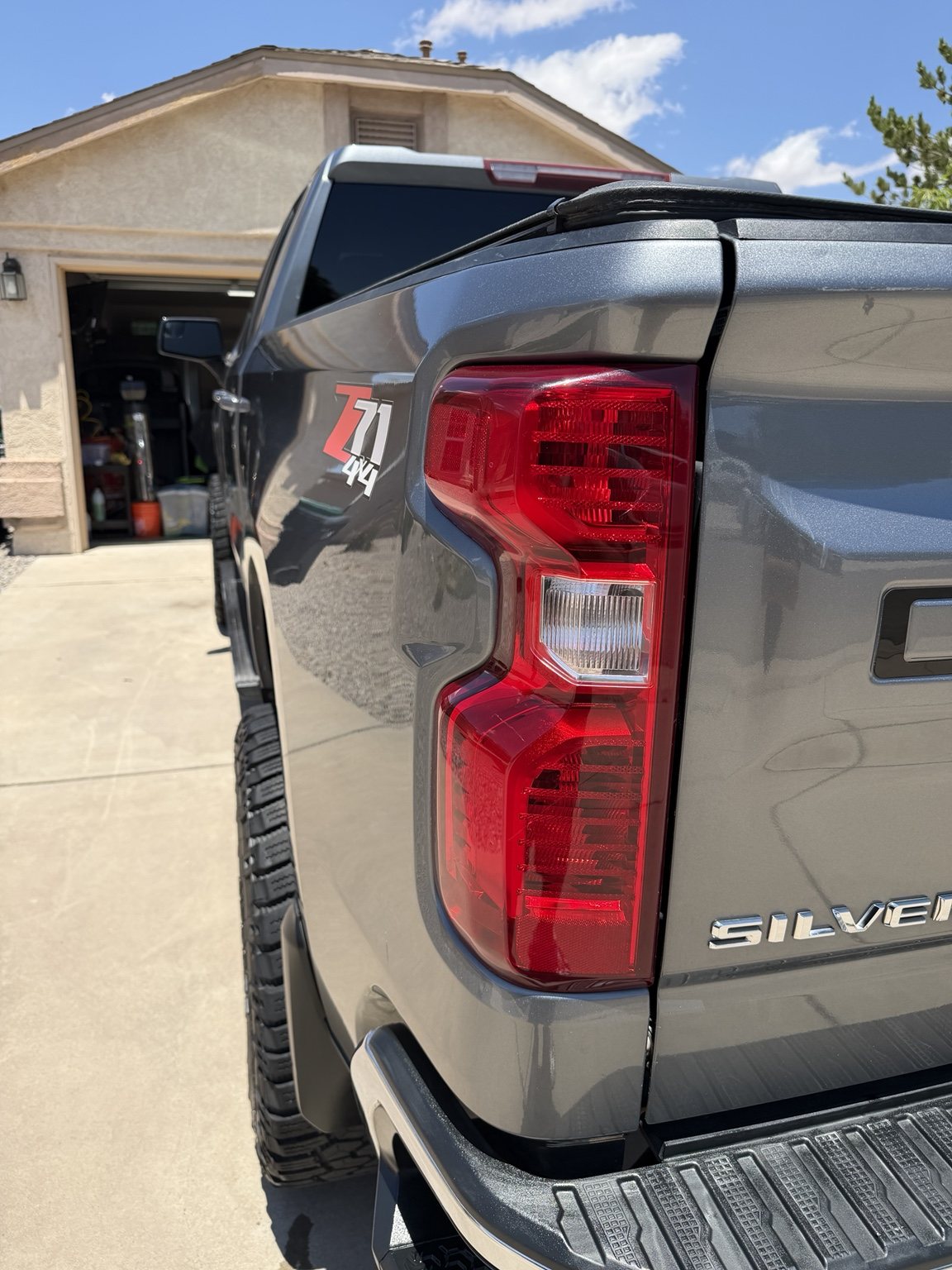 Clean silver Silverado bedside, taillight, bumper, and polished trim close-up
